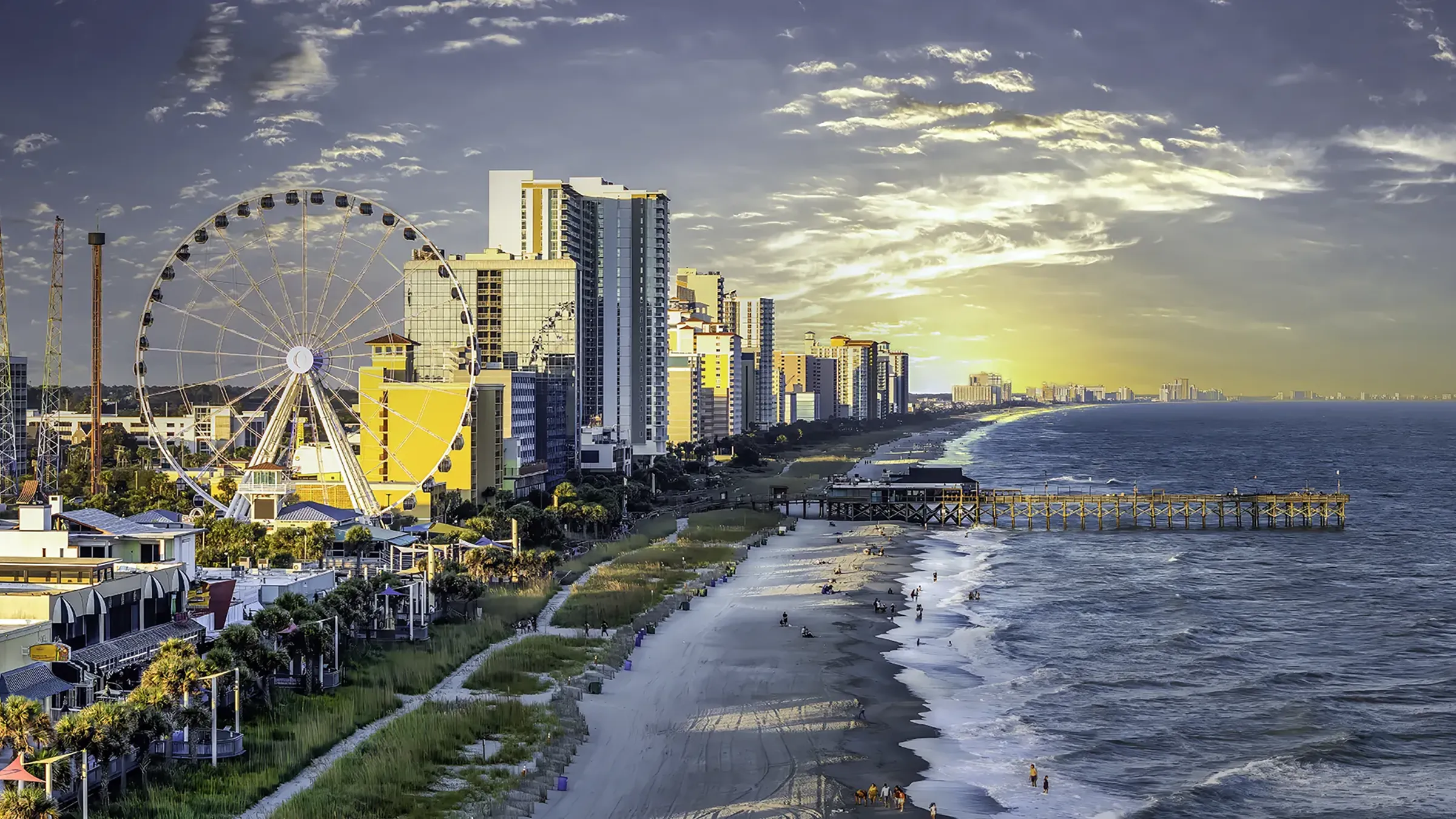 Beachfront skyline with Ferris wheel at sunset