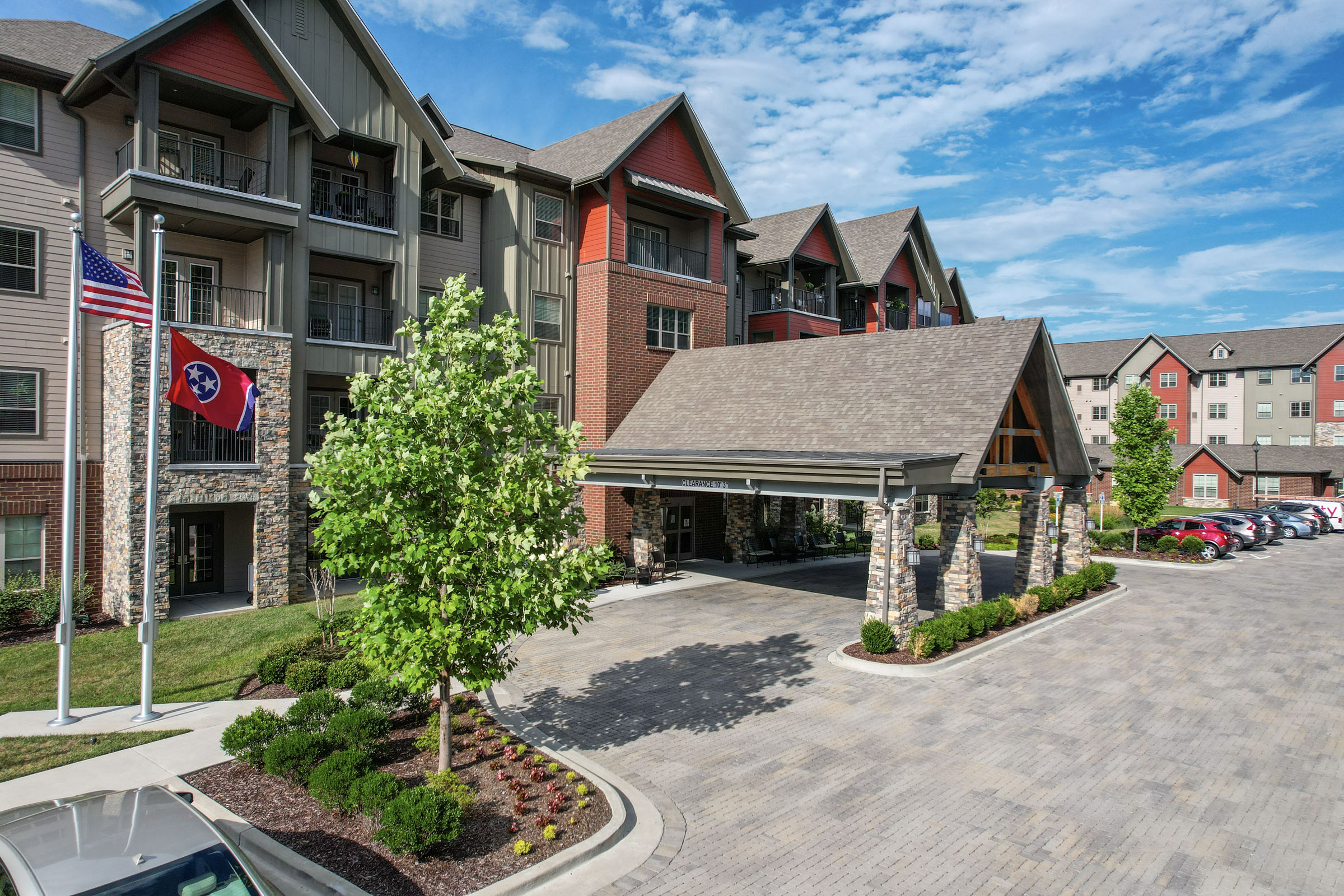 Modern apartment complex with covered entrance and flags