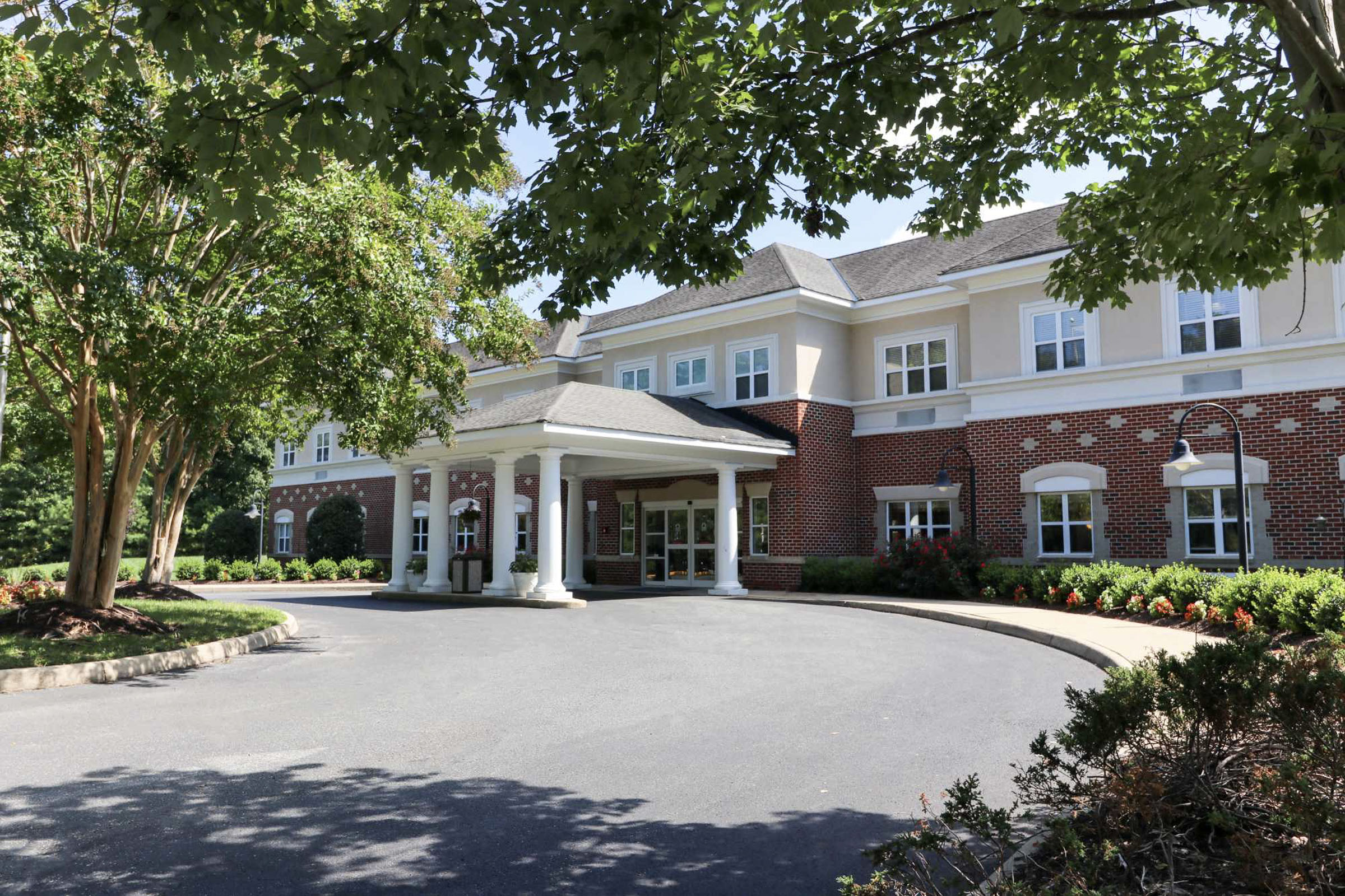 Brick building with white-columned entrance and driveway